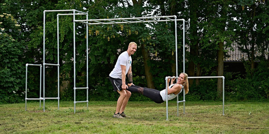 Sjov træning på udendørs træningsstativ | Kvinde og mand griner mens de styrketræner sammen