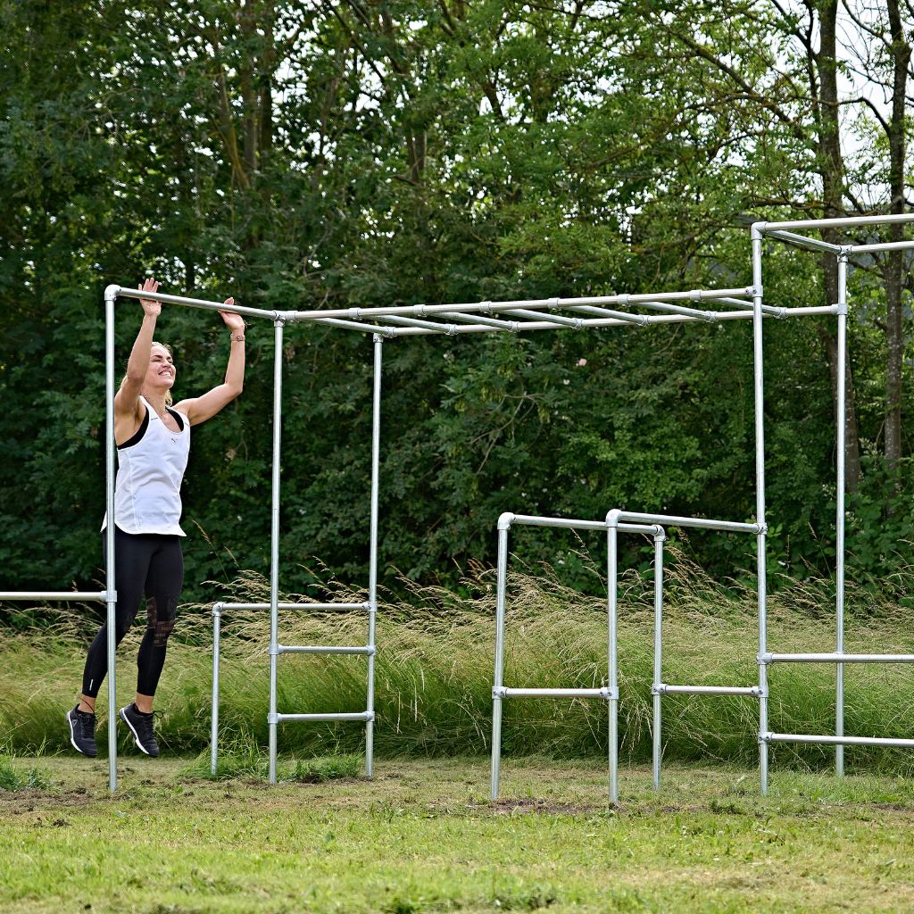 Kvinde hopper og laver burpee bar touches på udendørs træningsstativ