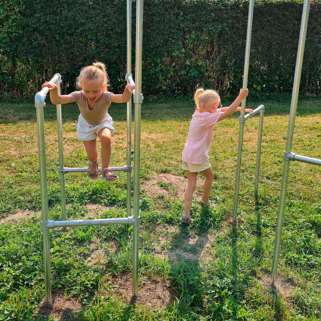 To piger leger og har det sjovt på træningsstativ i haven